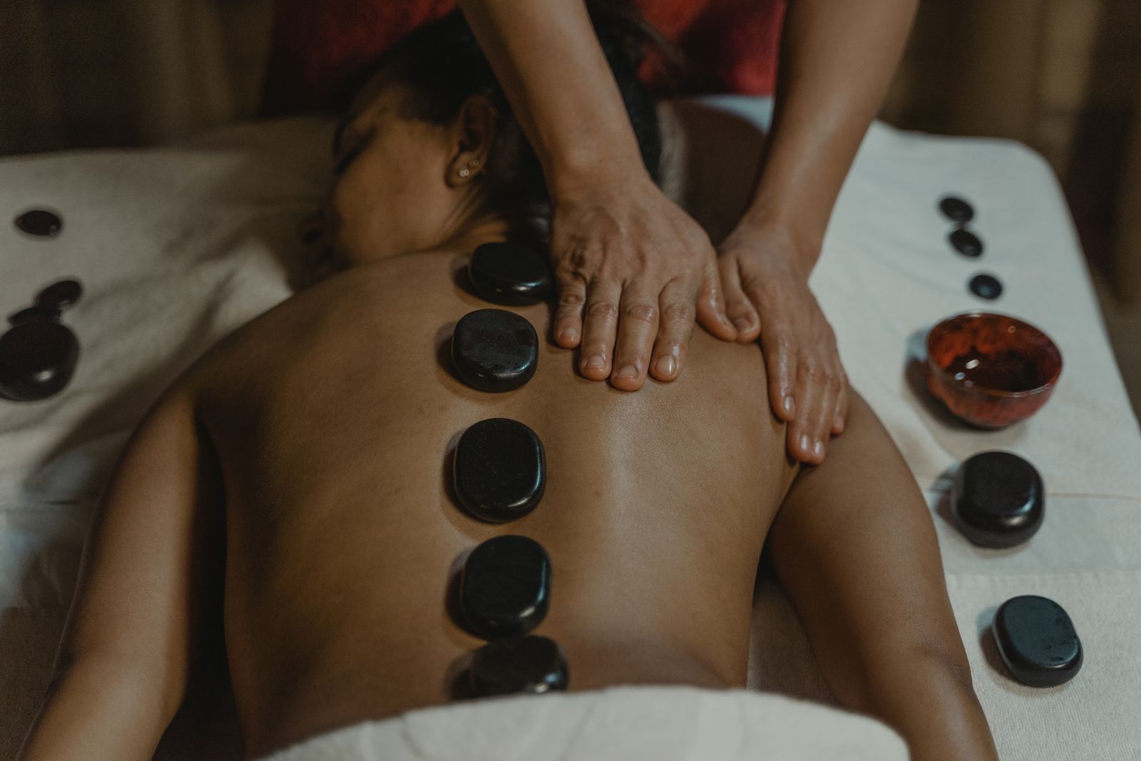 Massage du dos aux pierres chaudes, mains posées sur les épaules