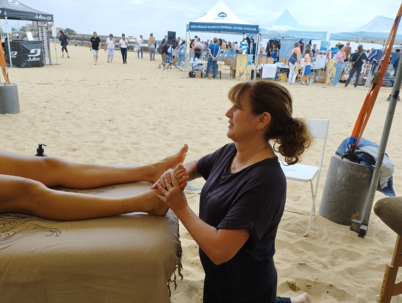 Caroline masse les pieds d’une sportive sur la plage, pendant un triathlon